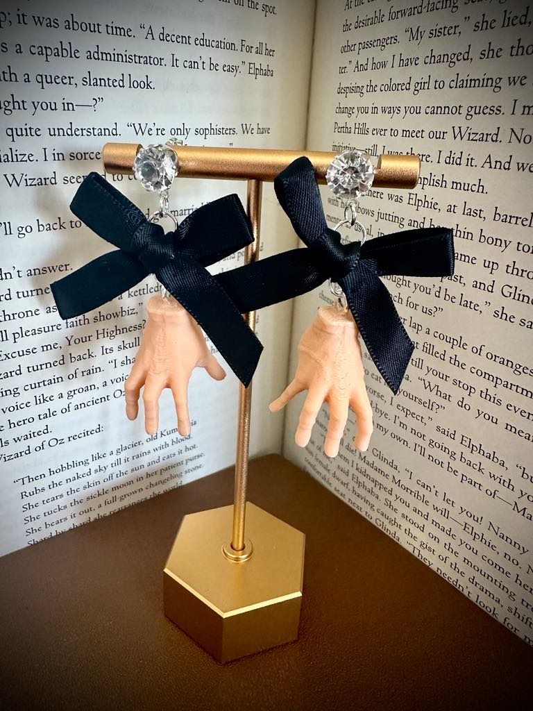Black bow earrings on a gold stand with a book background