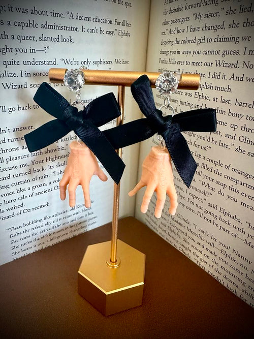 Black bow earrings on a gold stand with a book background